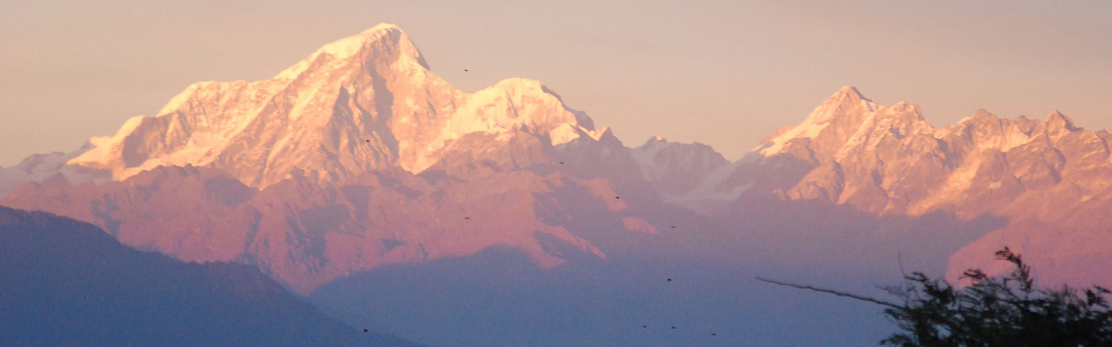 A hazy view of several snow-topped mountains. 